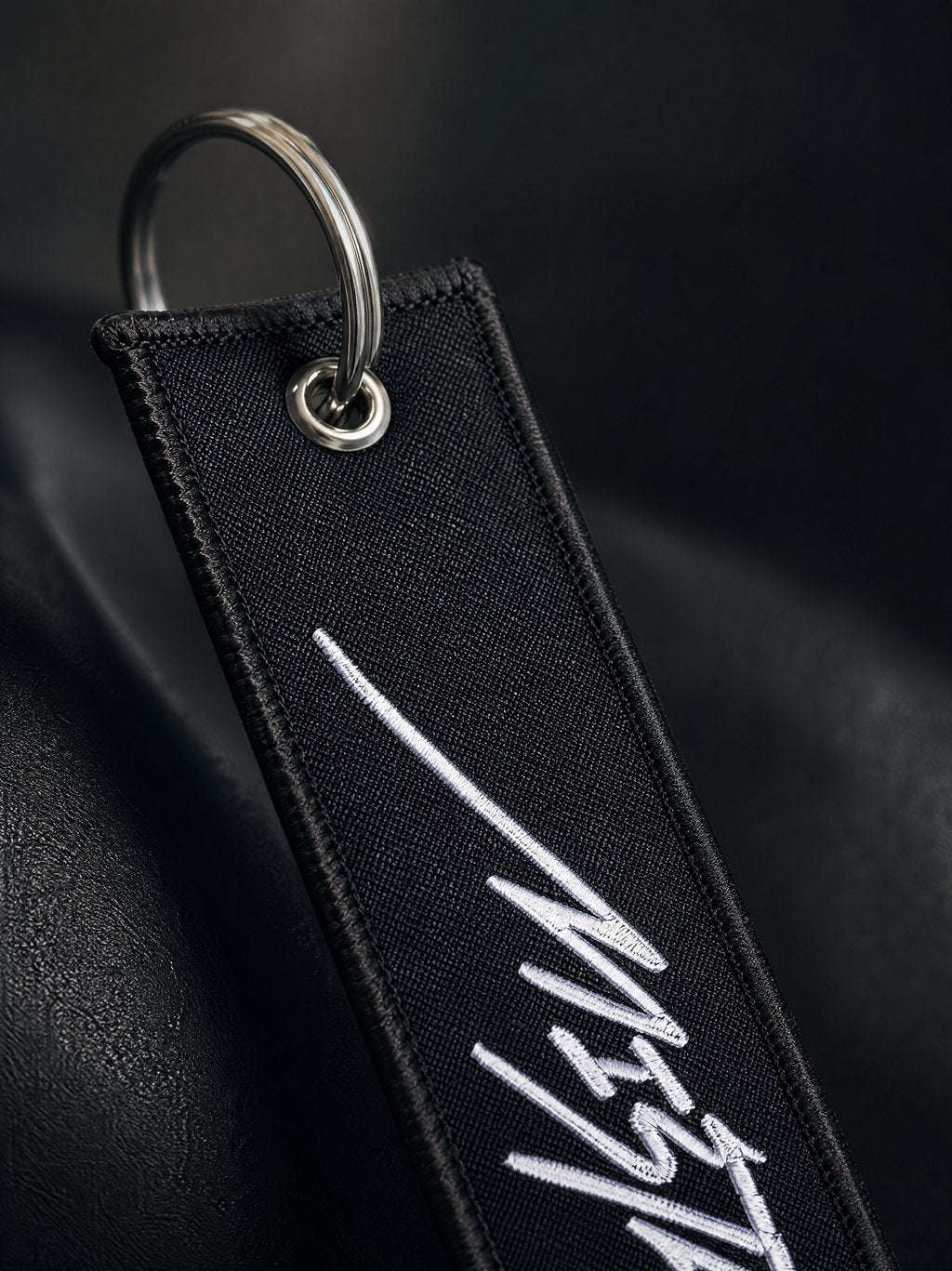 Black keychain with white text on a dark background