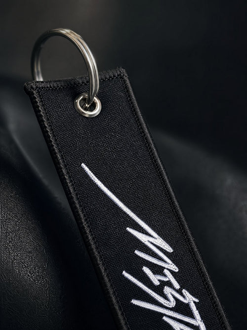 Black keychain with white text on a dark background
