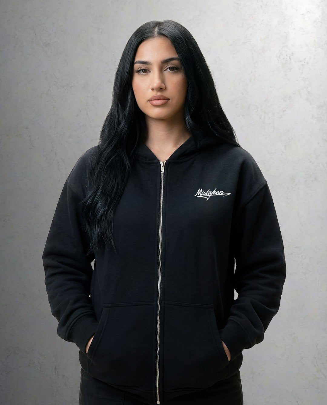Person wearing a black hoodie with a logo on a gray background