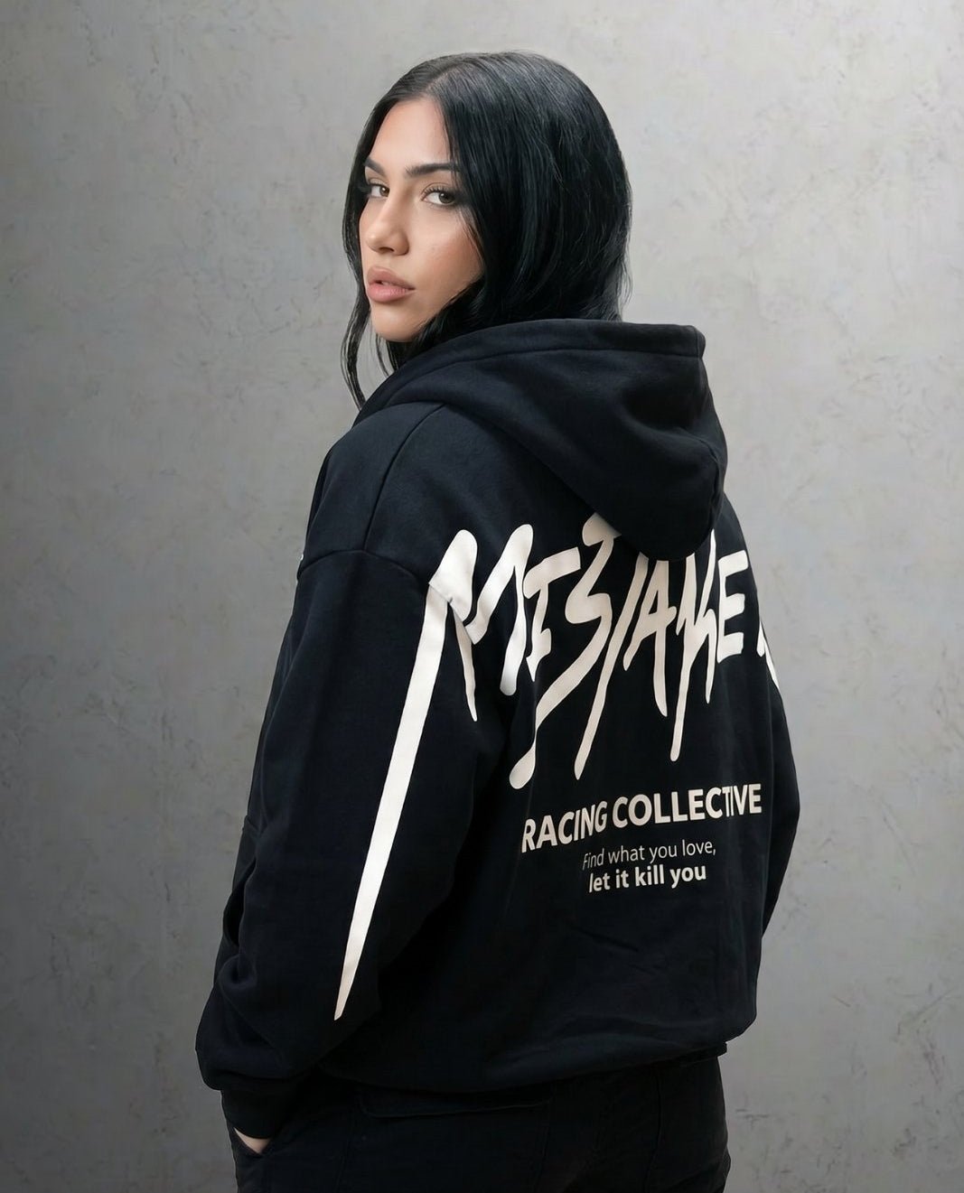 Person wearing a black hoodie with white text against a gray background