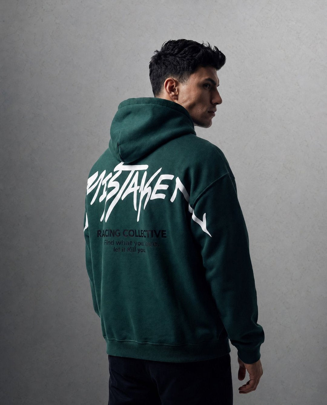 Person wearing a green hoodie with text on the back against a gray background