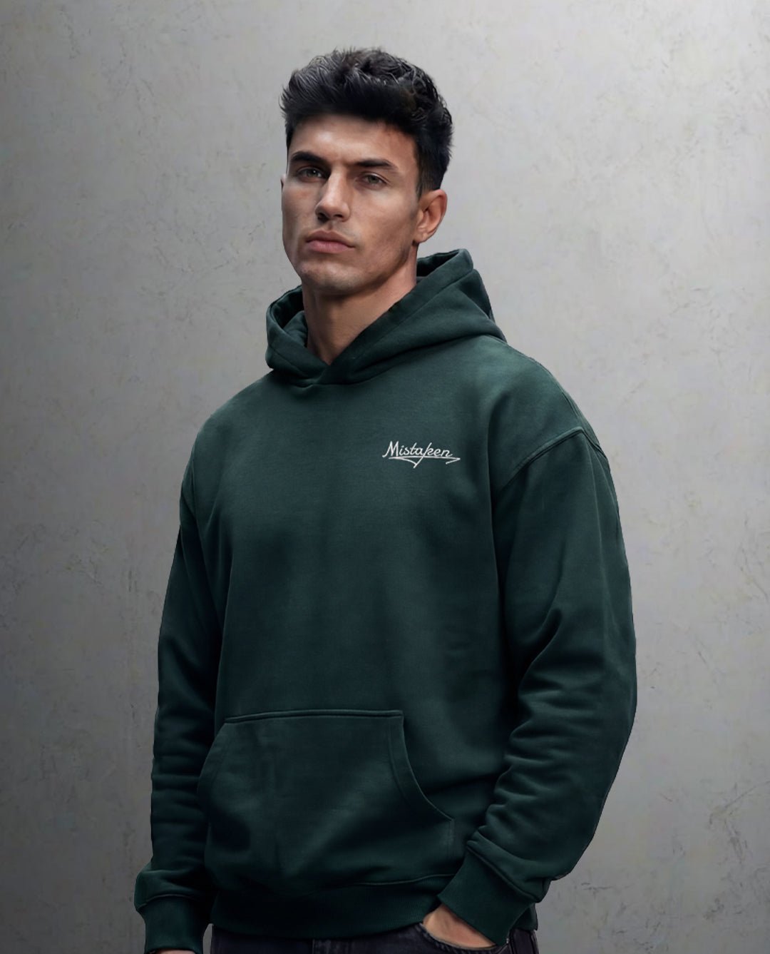 Man wearing a green hoodie with a brand logo against a gray background