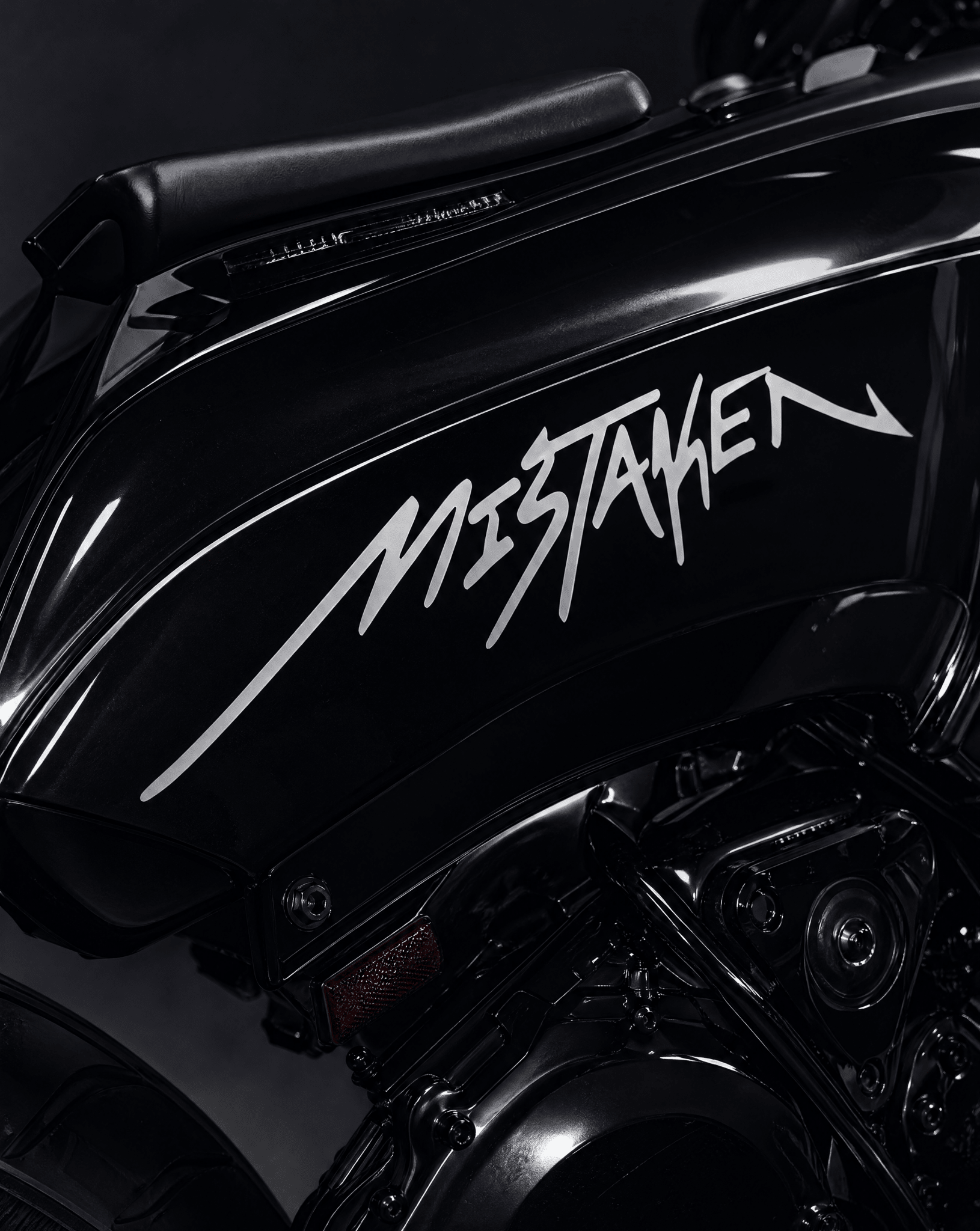 Black motorcycle with 'MISTAKEN' branding on a dark background